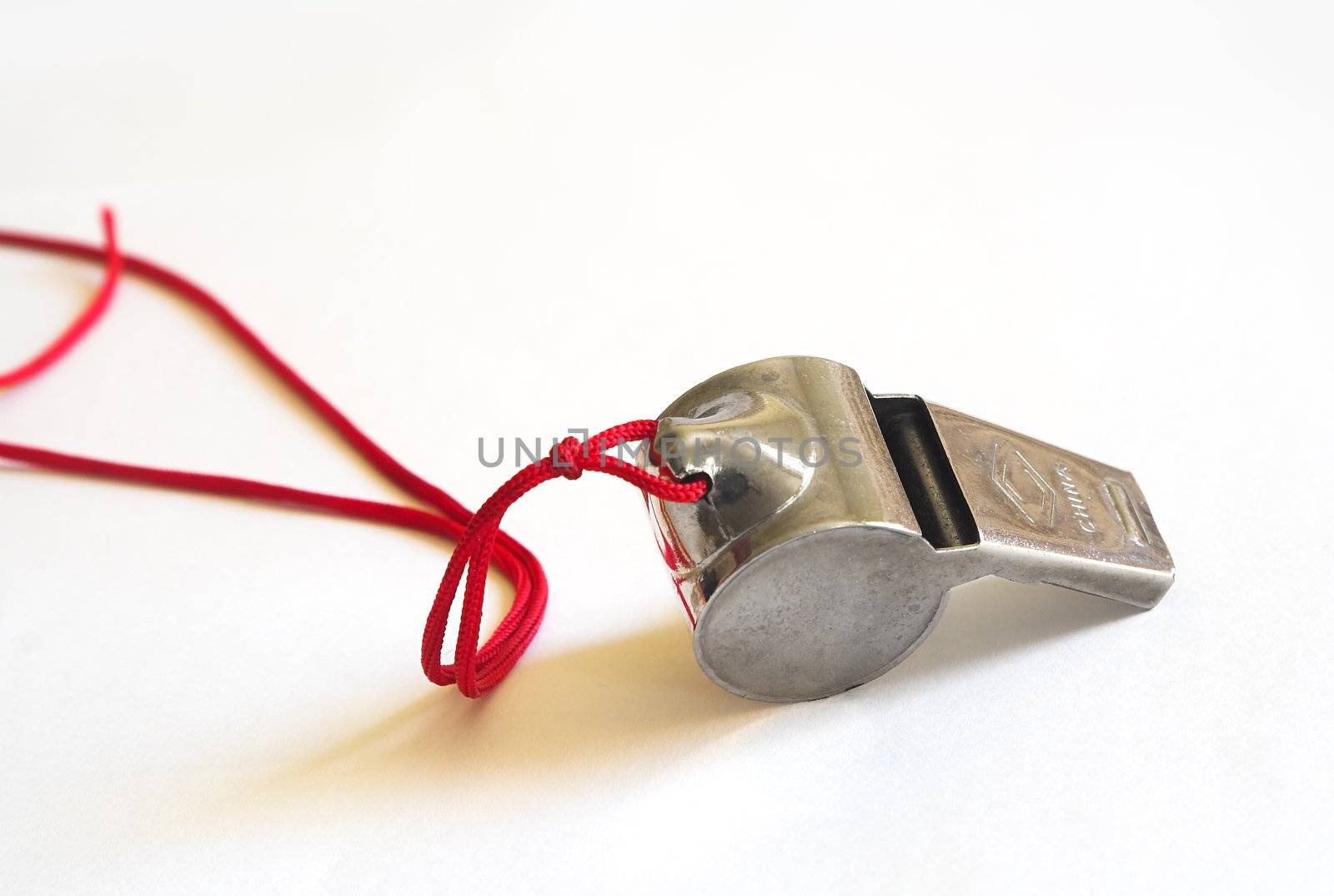 Metal whistle on a red cord shot on white background