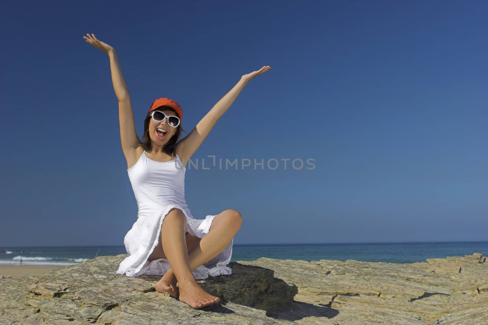 Beautiful happy woman on the beach with a orange hat and white glasses