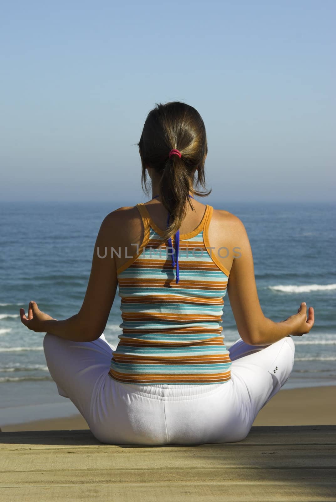 Beautiful young woman doing yoga on the beach