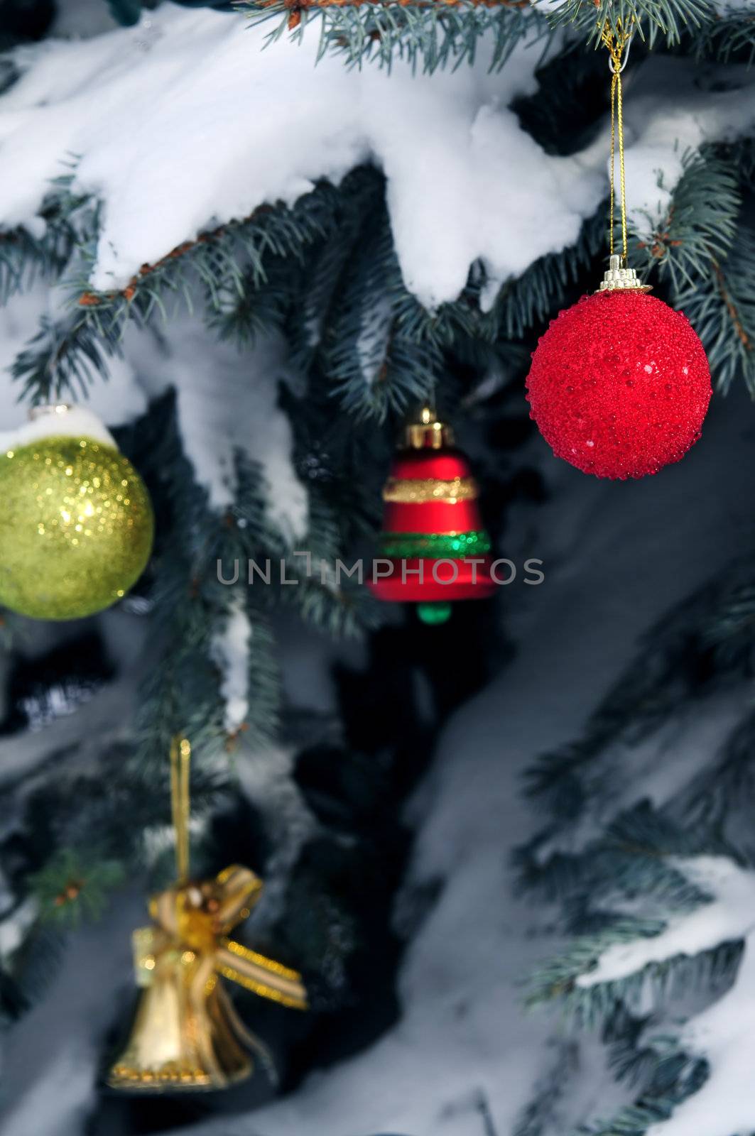 Christmas ornaments hanging on snow covered spruce tree outside