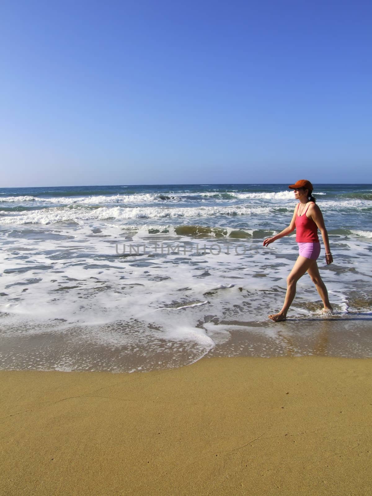 Woman brisk-walking along beach in the Mediterranean