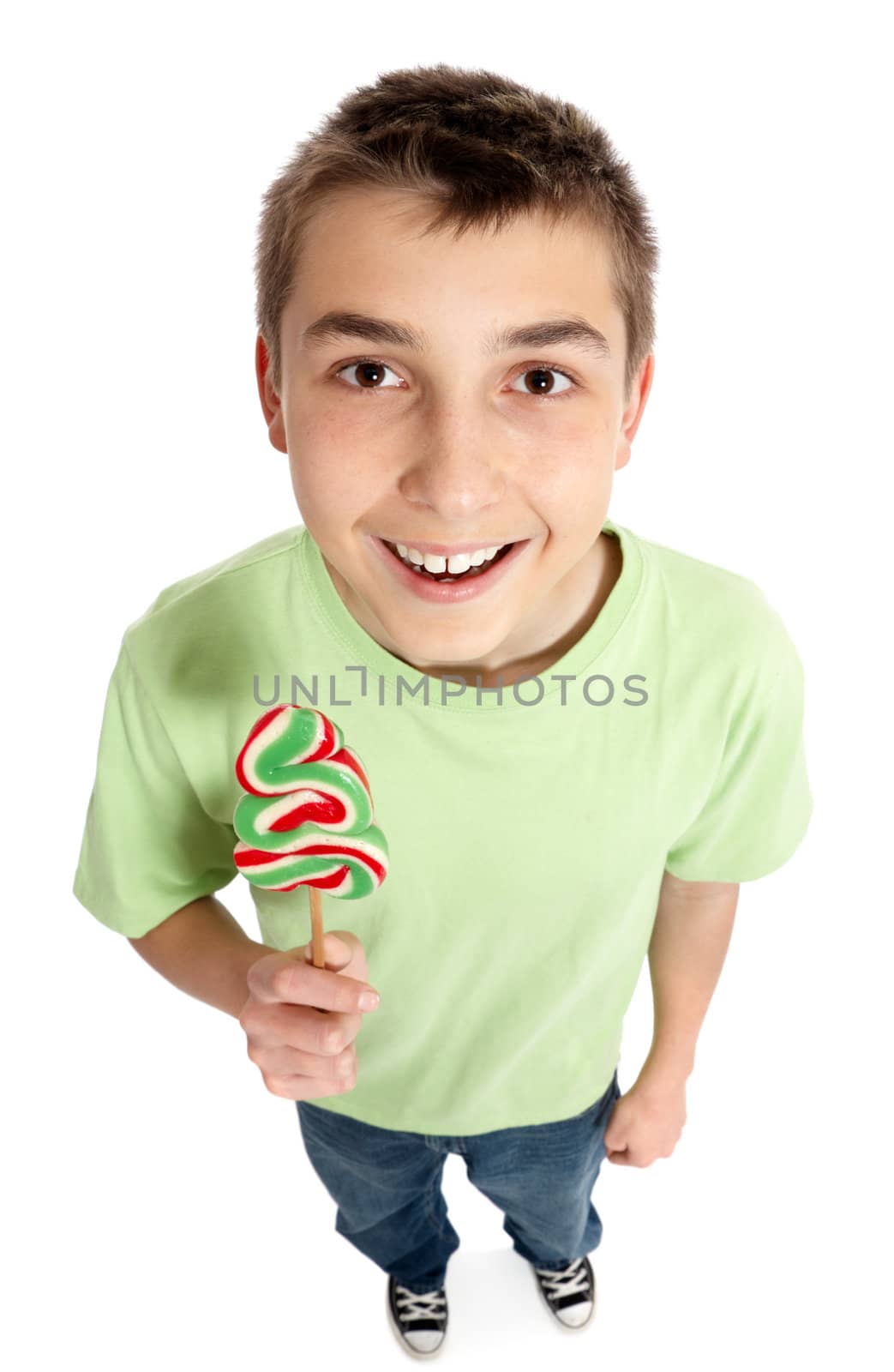 Cheerful boy holds a swirly green red and white lollipop shaped like a Christmas tree