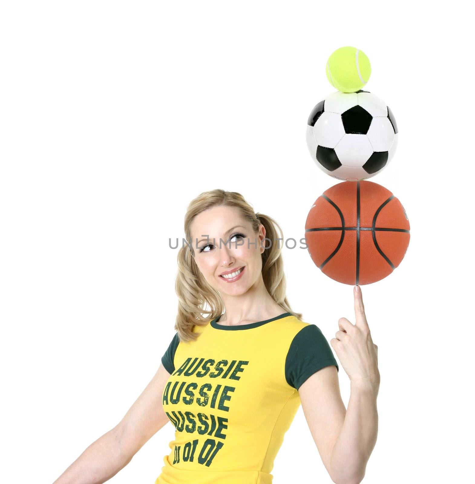 Cheerful, Aussie girl in green and gold balancing sporting balls.
