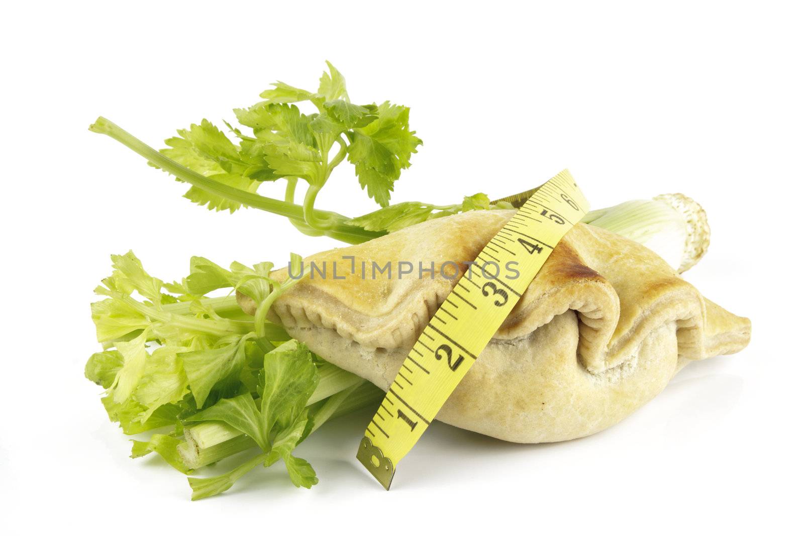 Contradiction between healthy food and junk food using celery and pasty with a tape measure on a reflective white background 