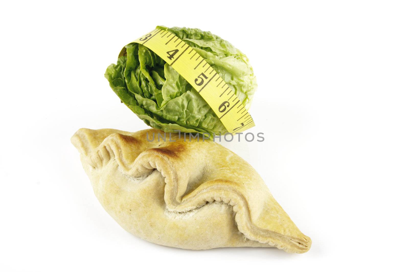 Contradiction between healthy food and junk food using a green salad lettace and pasty with a yellow tape measure on a reflective white background 