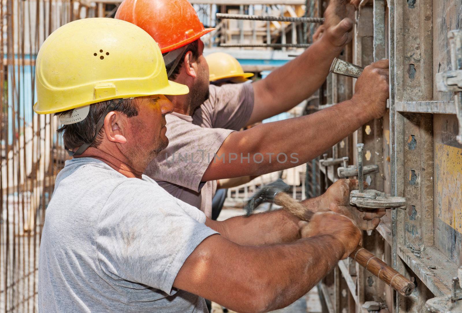 Authentic construction workers positioning cement formwork frames in place