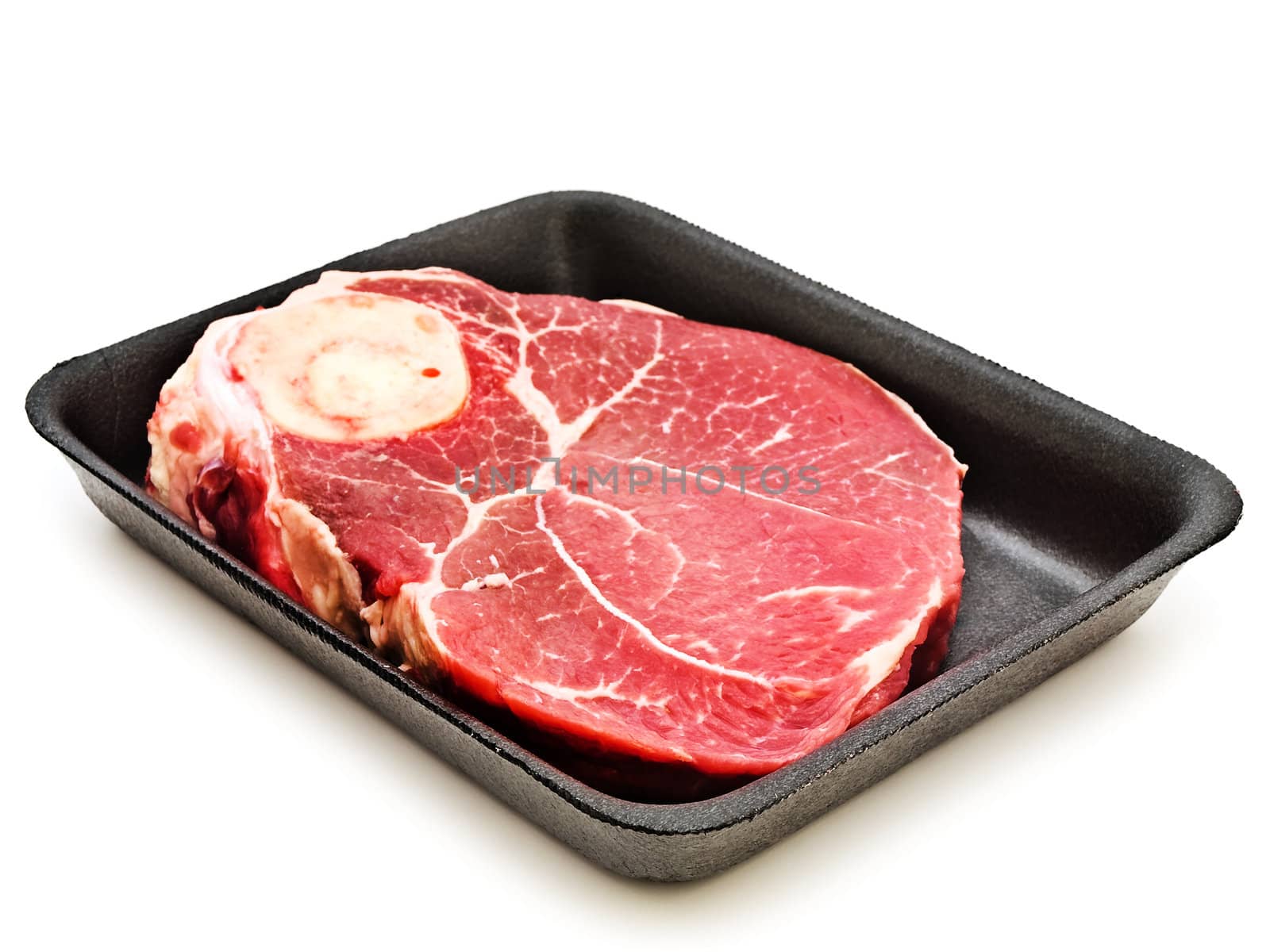 Big piece of raw meat at plastic plate against the white background 