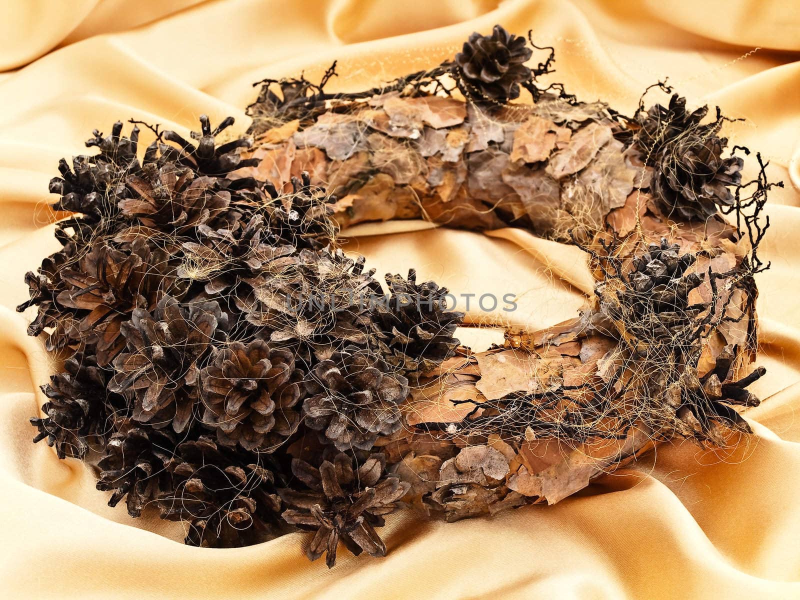 Handmade garland with natural decorations over golden textile background  