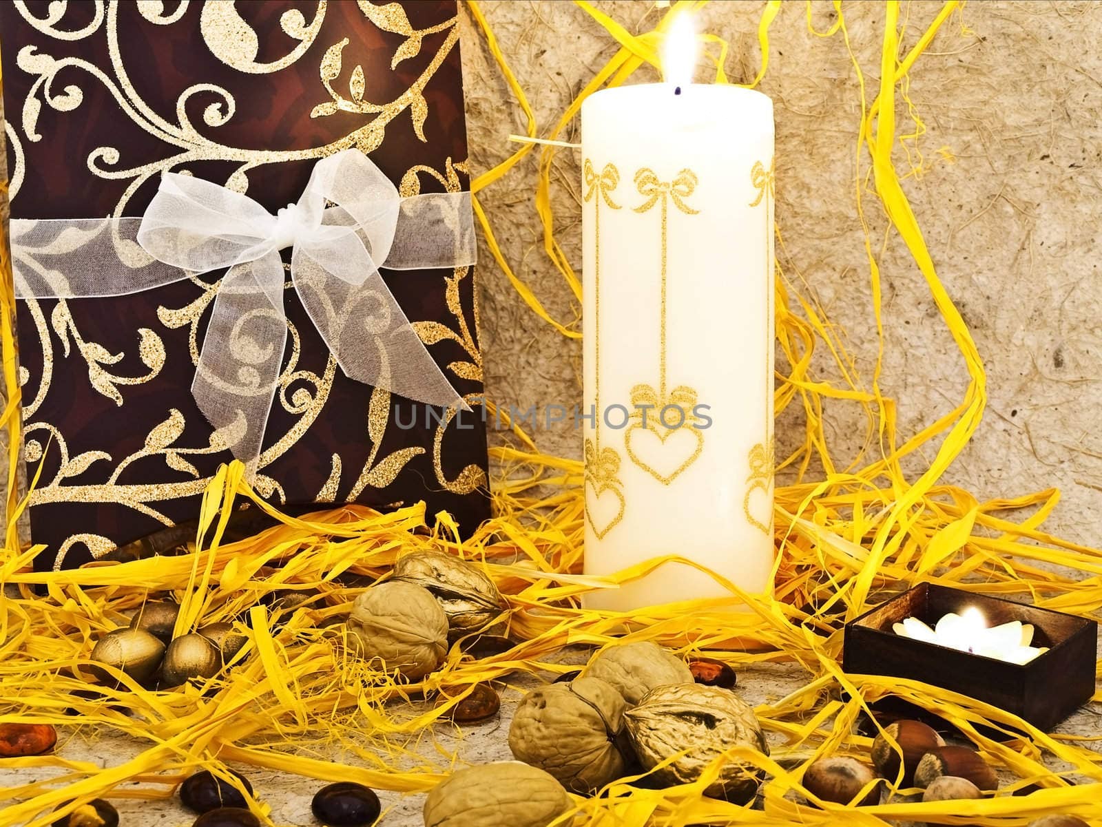 Photo of holiday decoration with gift box, candles and nuts against beige background  