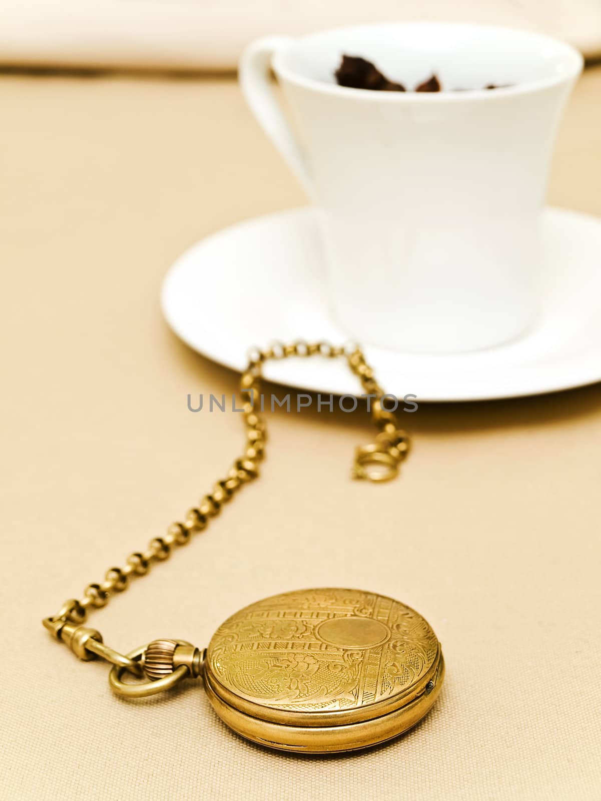  old pocket watch near the cup of tea at beige 