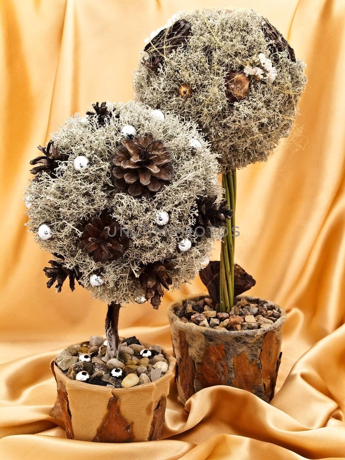 two decorative handmade natural materials trees against the golden textile background 