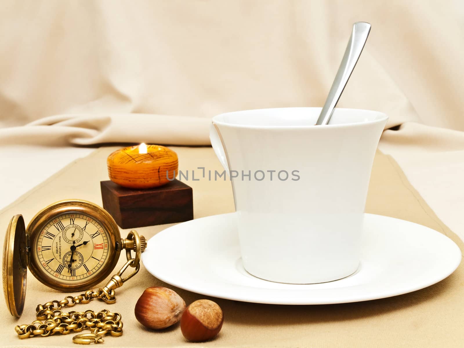 original decorated table serving with candle, nuts and old pocket watch near cup at beige  