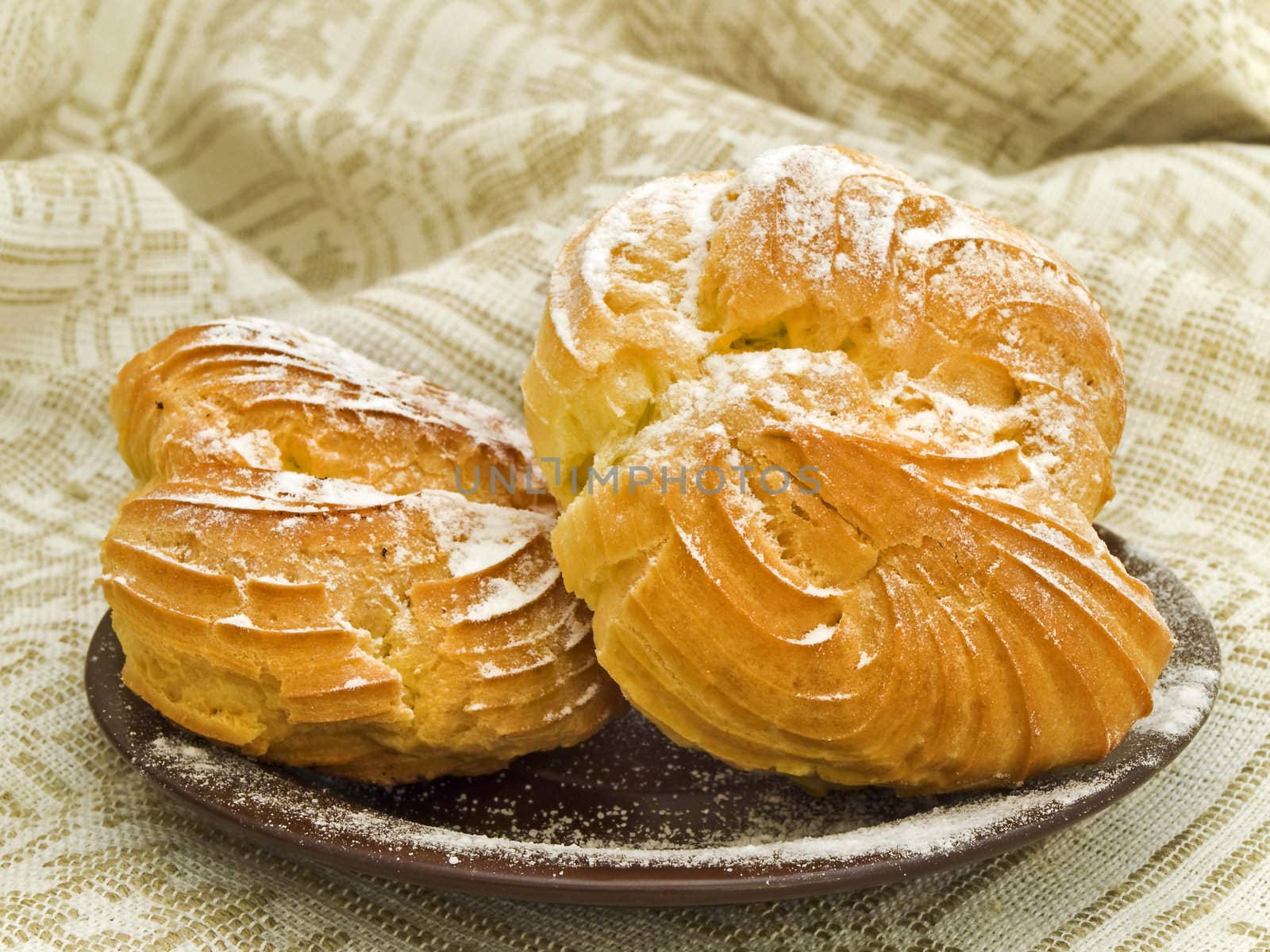 Two tasty buns with sugar powder against the linen background 