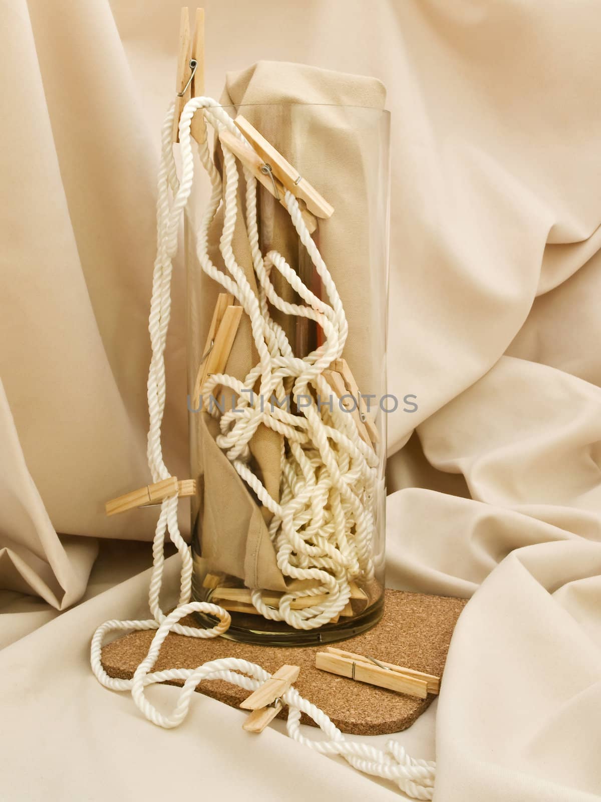 Composition with clothespins, cord and vase against beige textile background