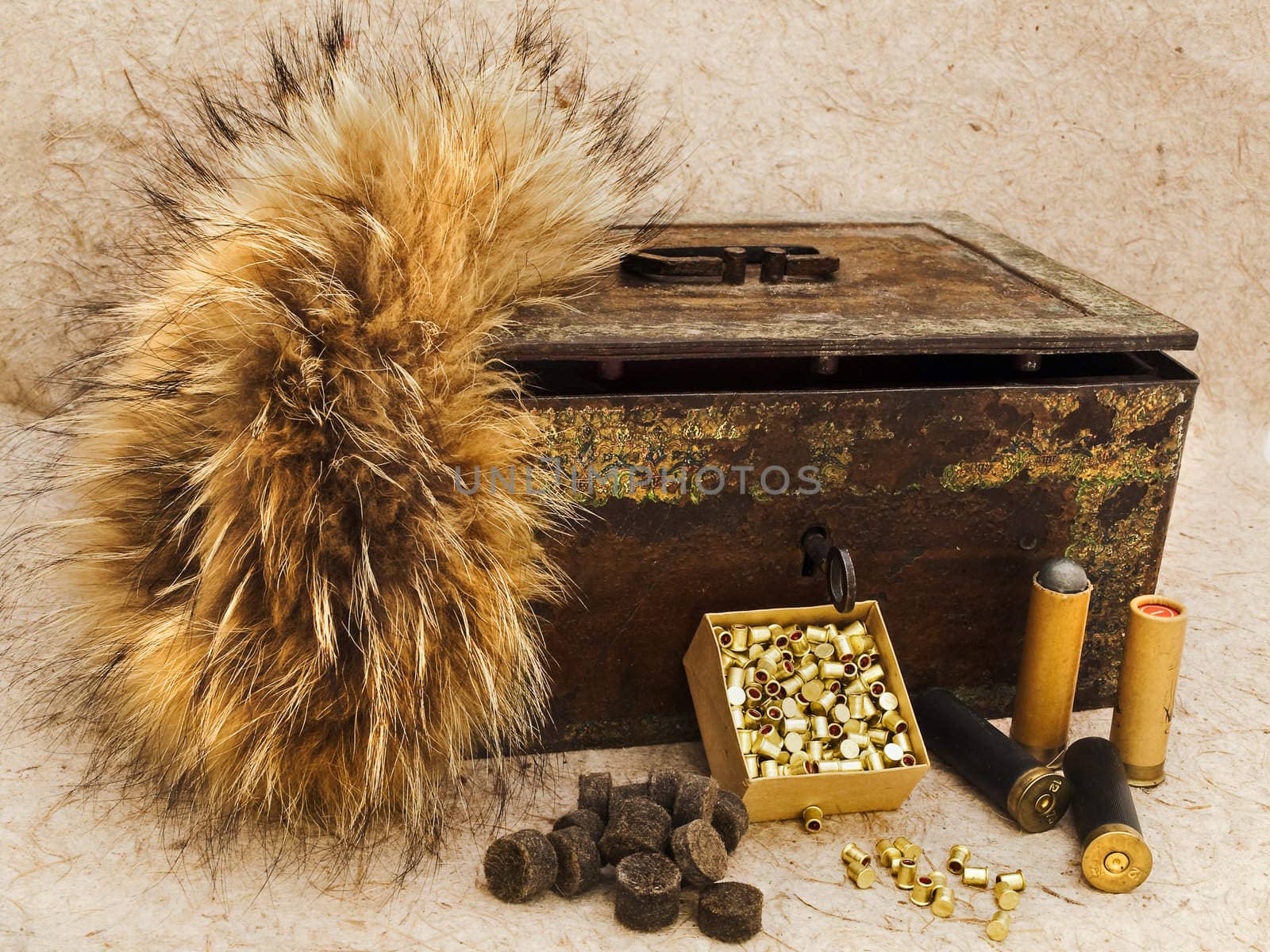 Photo of old cartridge for hunting rifle and vintage rusty chest with fox brush against beige background