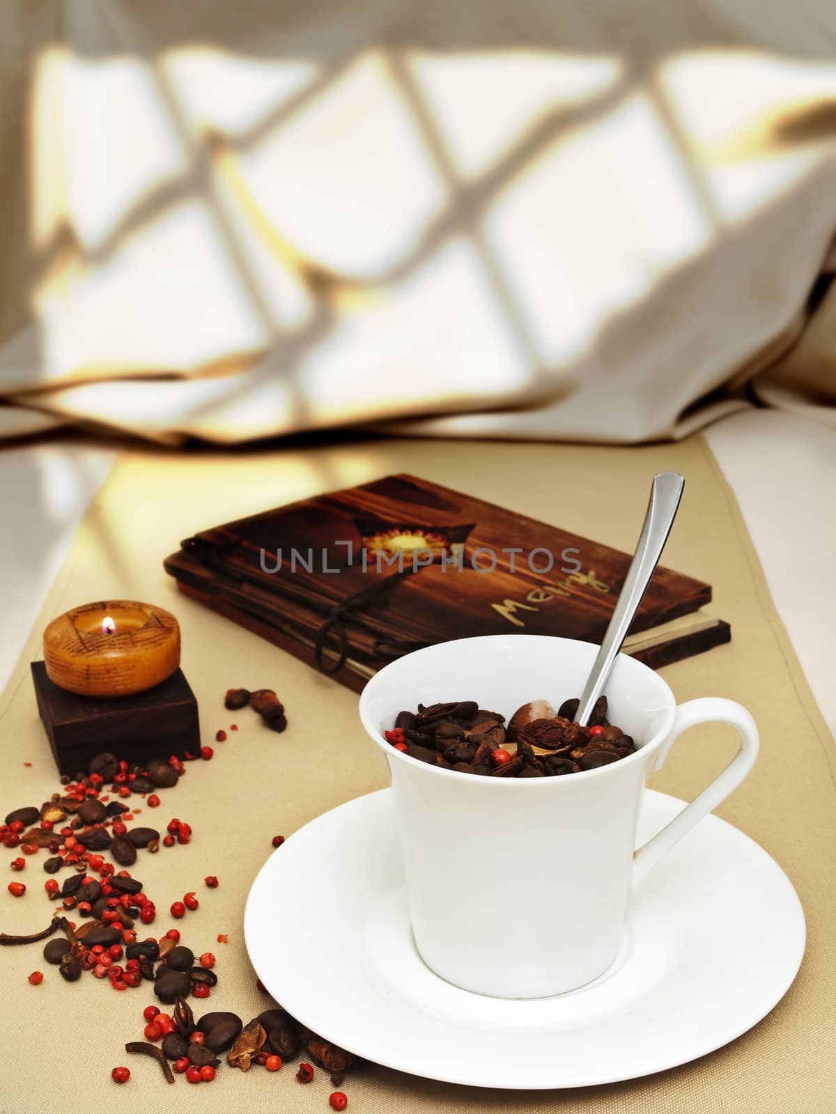 decorated table serving with burning candle, coffee beans near cup at beige