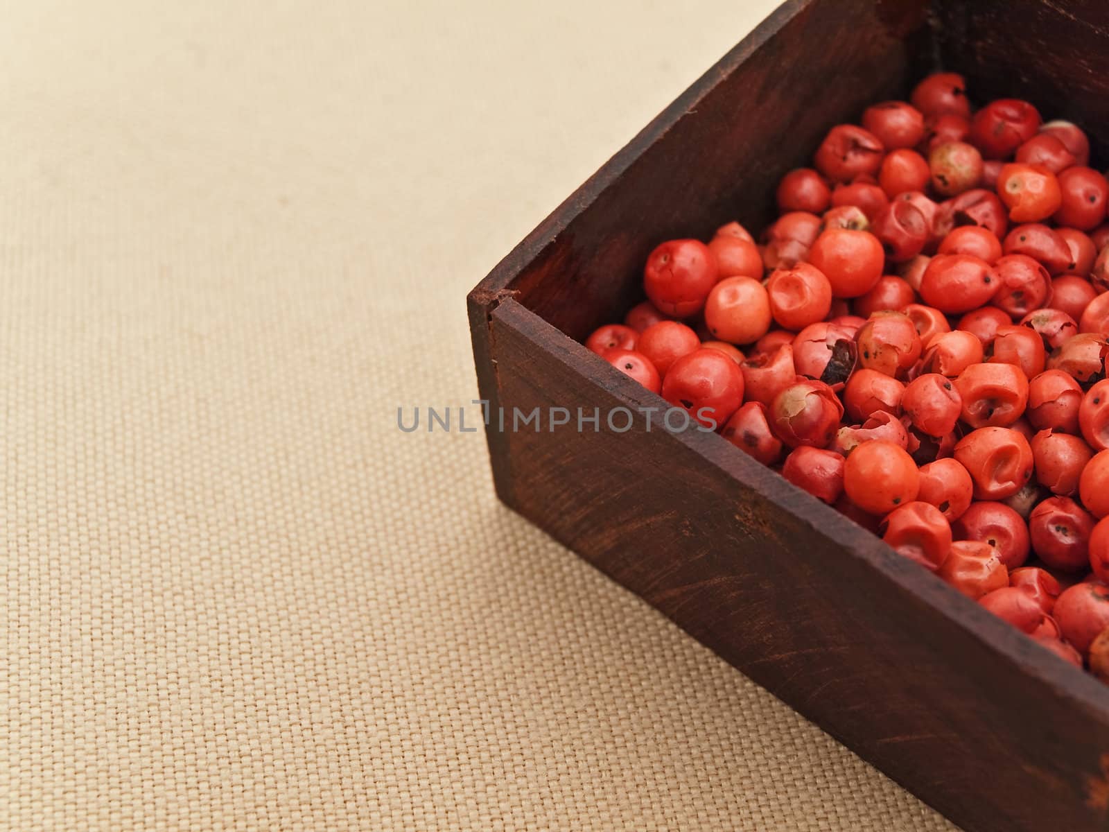 red pepper seeds in wooden box at beige textile