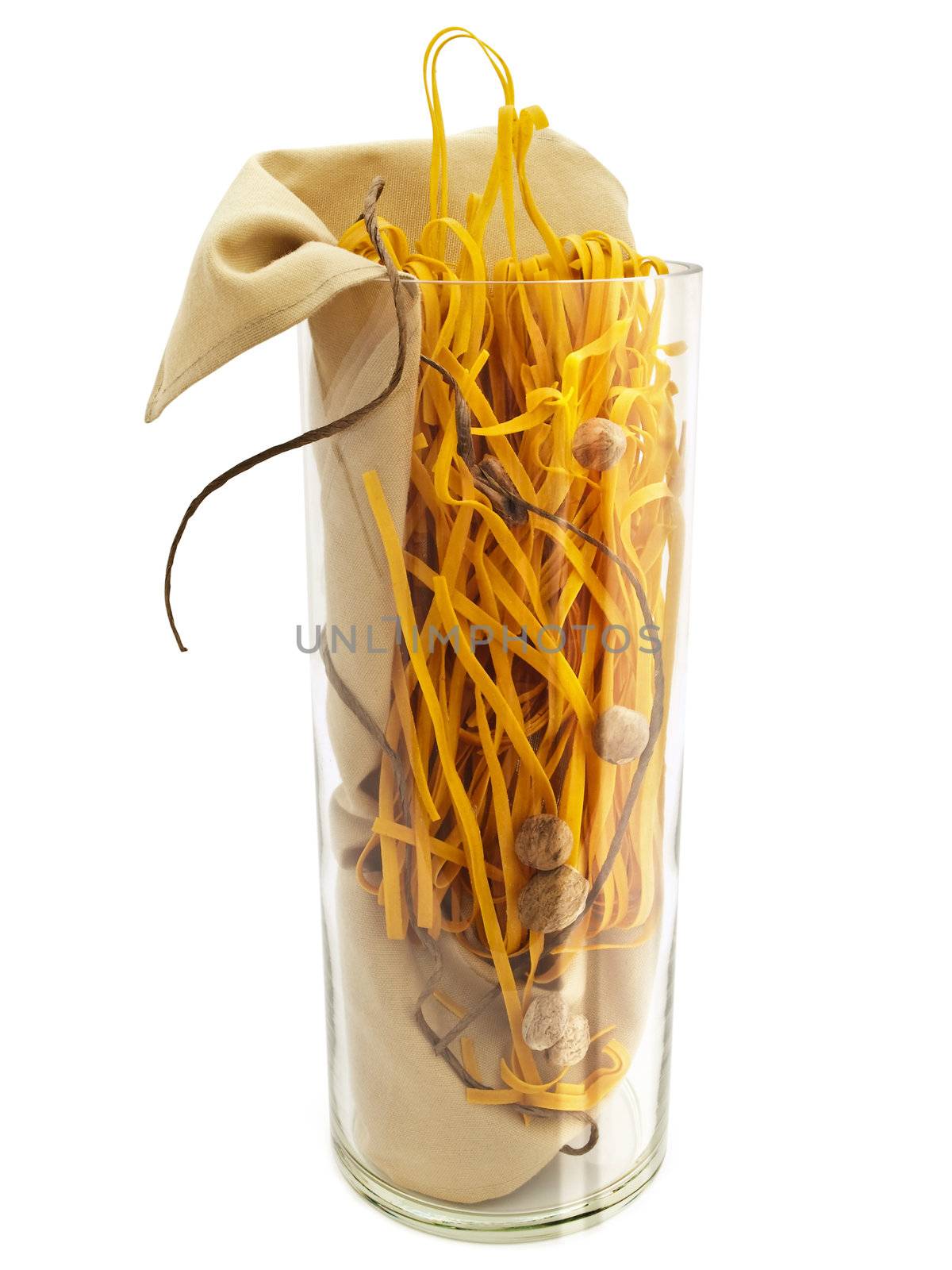 chili pasta with nutmegs in glass vase against white