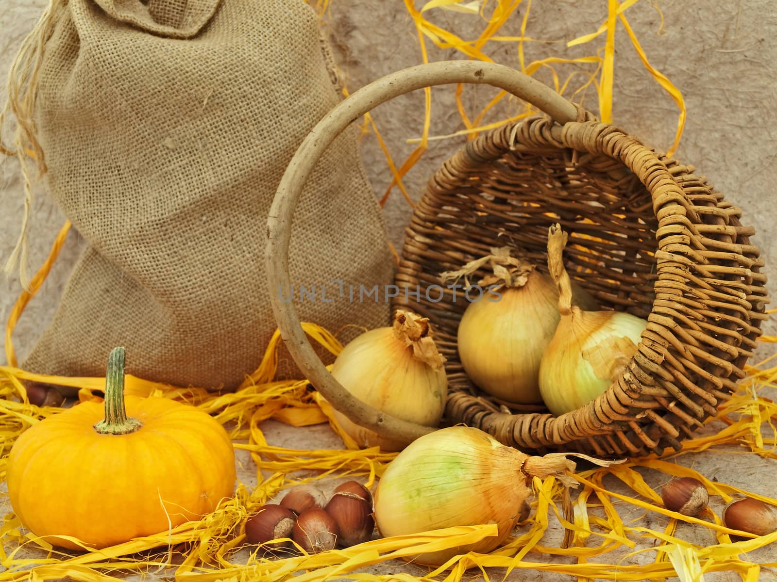  still life with pumpkin, onion in basket and nuts against beige background  