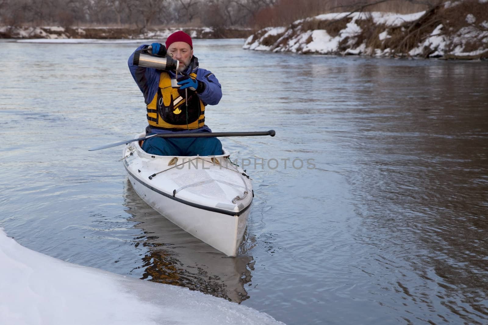 winter canoe paddling on icy river, taking a break for hot tea (South Platte River in eastern Colorado)