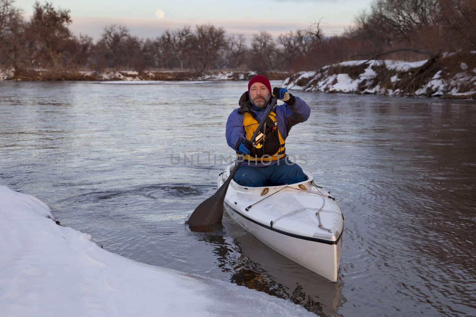 paddling canoe on a winter river by PixelsAway
