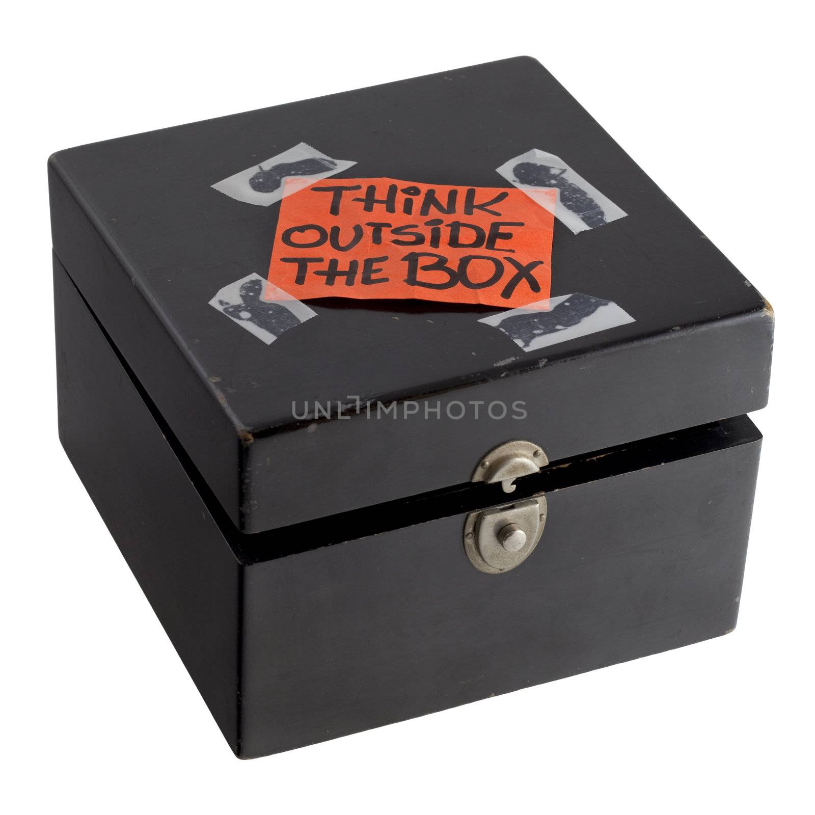 think outside the box - orange label (reminder note) casually taped on top of old black painted wooden box with dents and scratches, isolated on white with clipping path