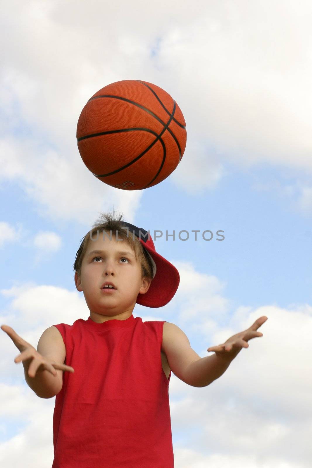 Boy in a red tank top catching a ball.  Shot against a cloudy sky, afternoon  Focus on face and ball, hands in motion
200 iso
