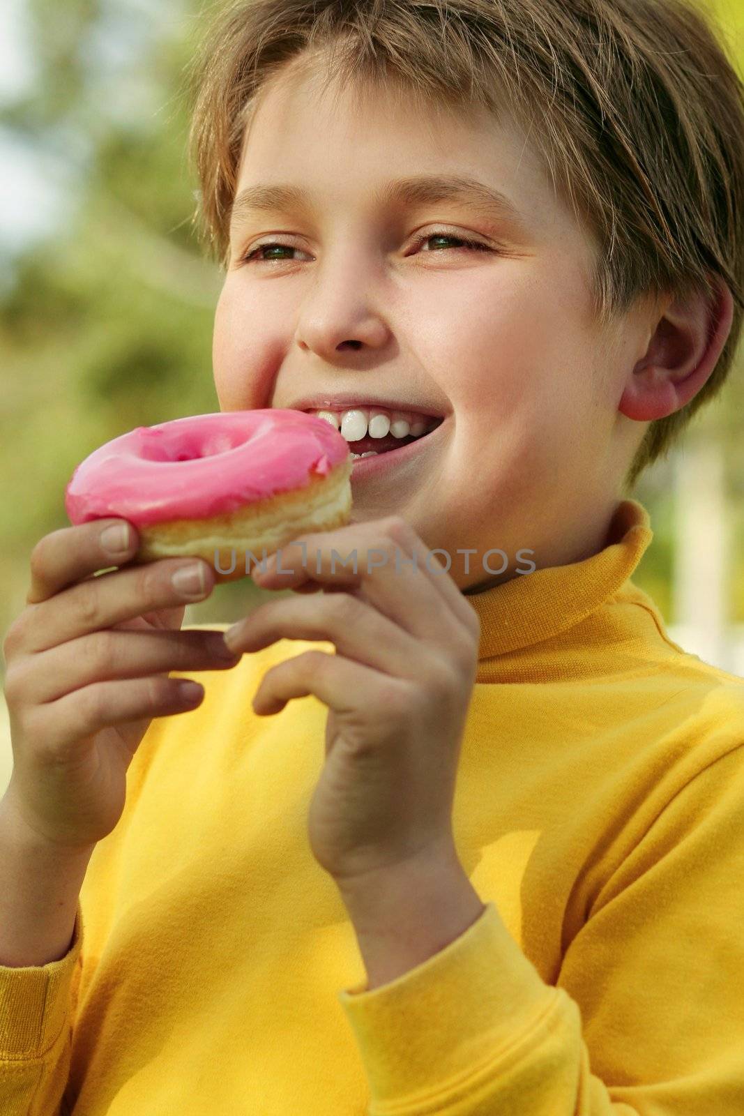 A child eating a pink iced doughnut