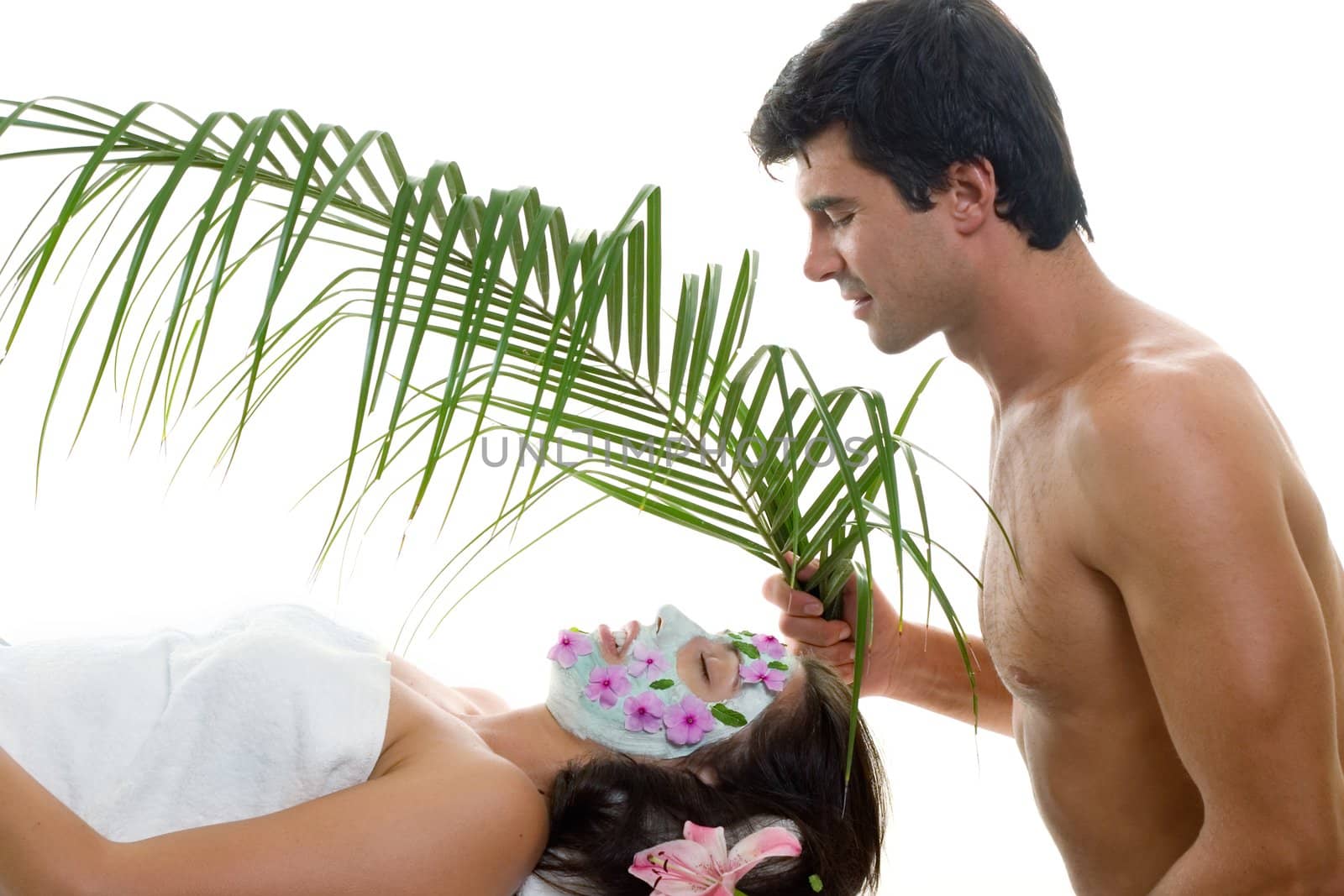 A young woman is gently fanned with a palm frond at a day spa,  exotic resort salon or perhaps she is pampered by her husband or lover