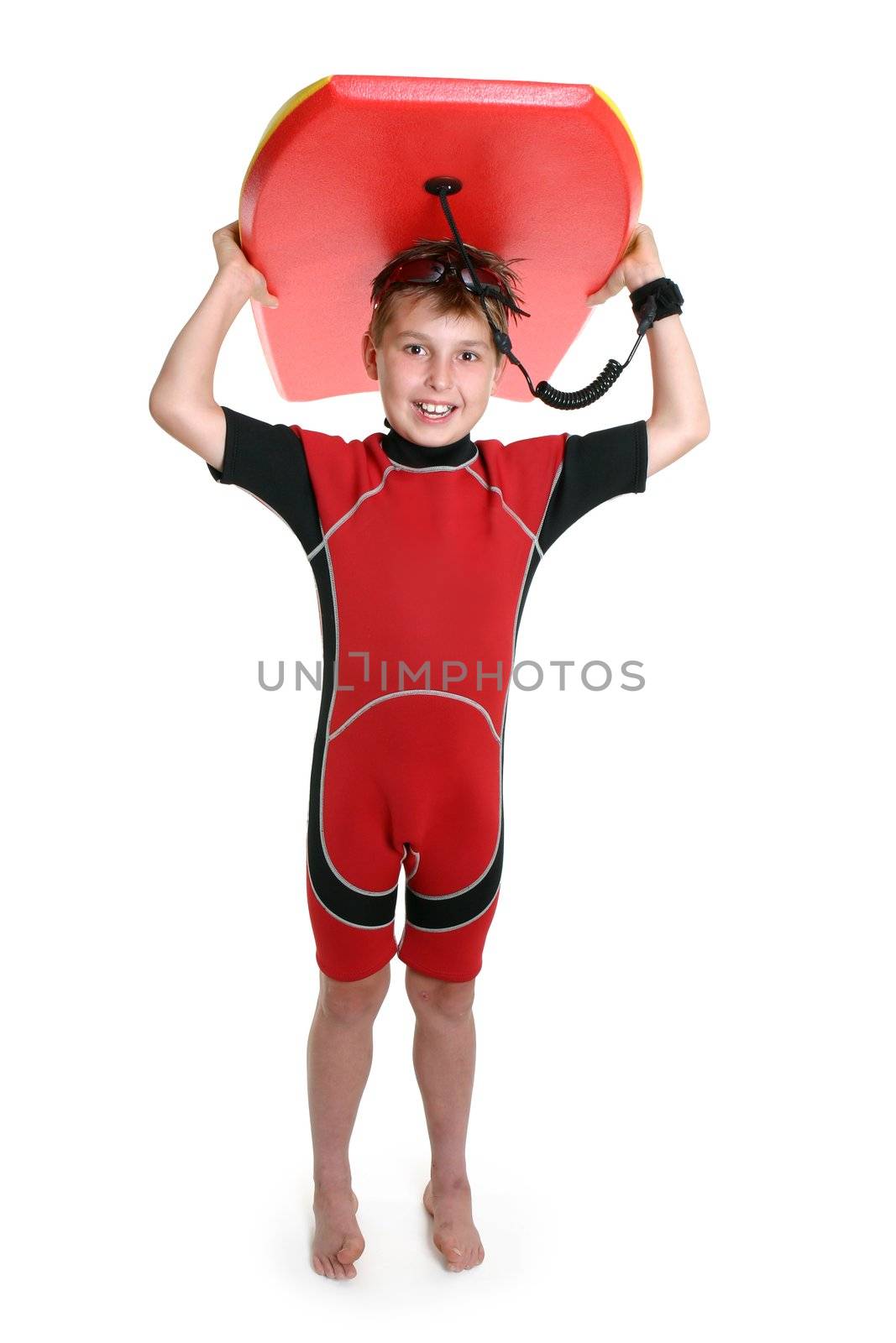 A child carrying a bodyboard over his head and smiling