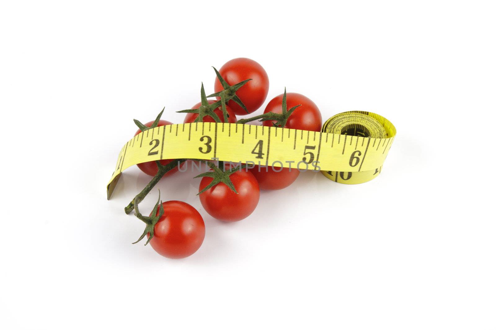 Small red ripe tomatoes on the vine with yellow tape streamer on a reflective white background