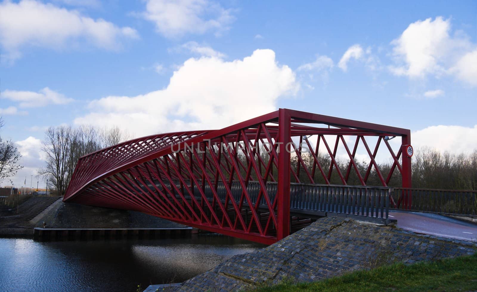 Red bridge with a twist and blue sky with clouds