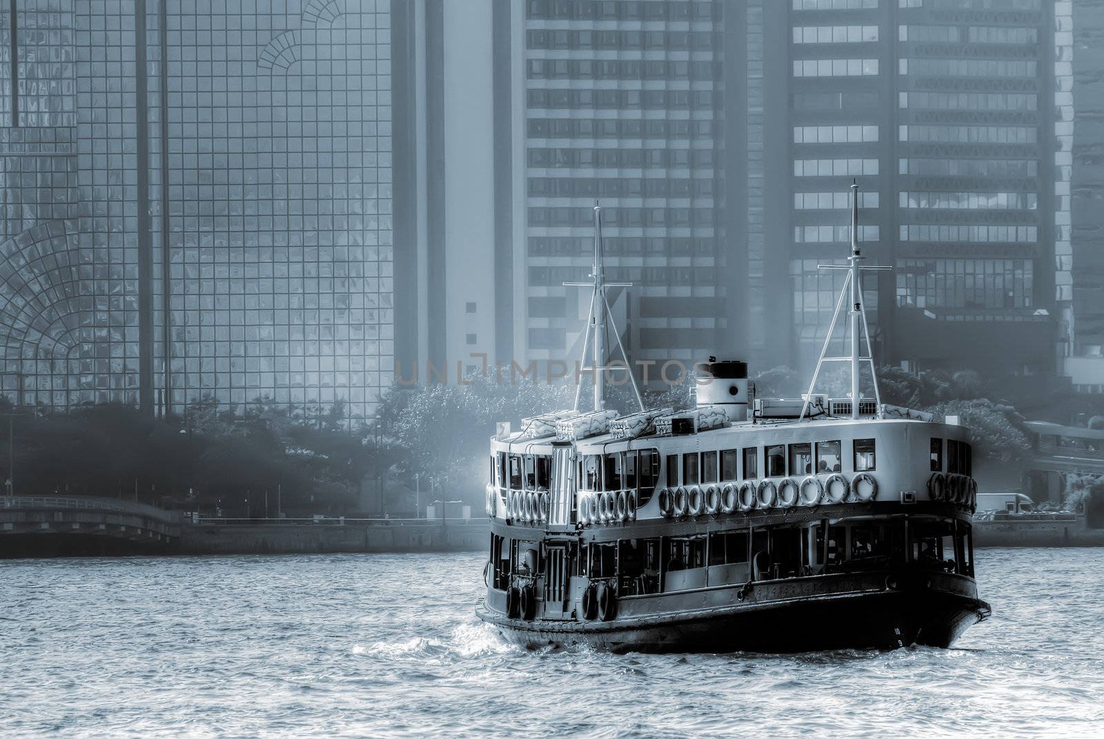 Barge on port in Hong Kong with tall buildings.