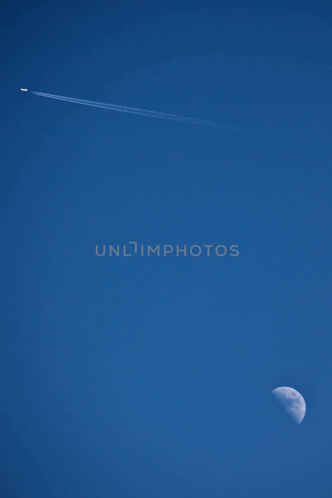 Moon and an aeroplane with a blue sky