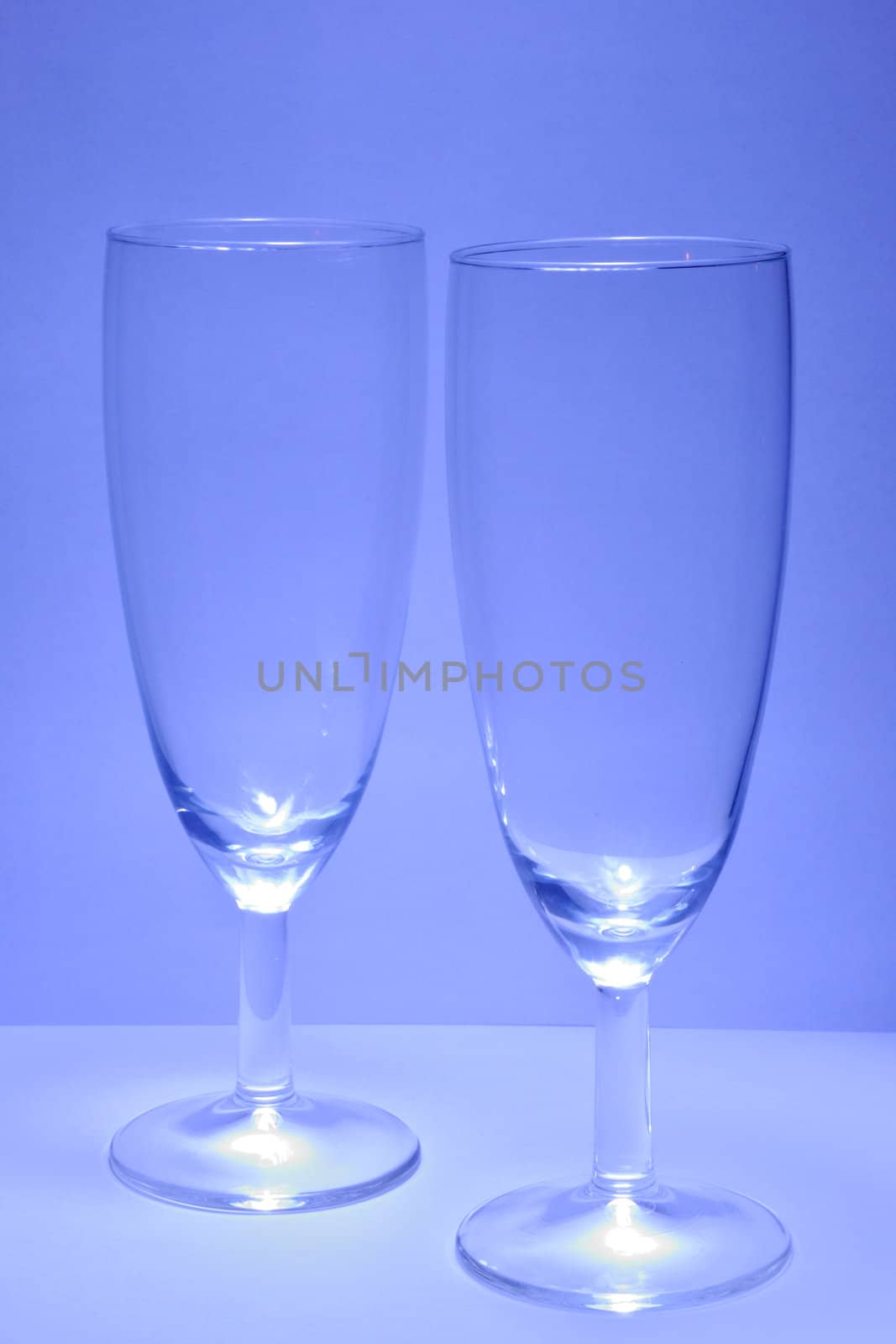 Two transparent glasses of wine on the blue background. 
