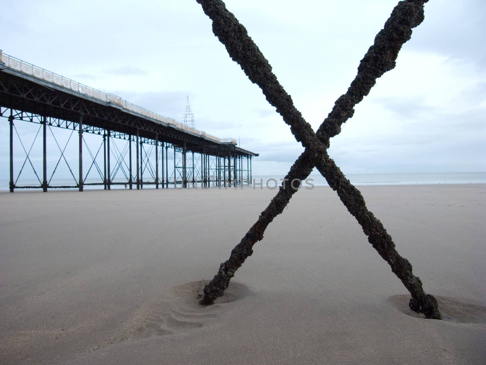 X on the beach with abandonned pier.