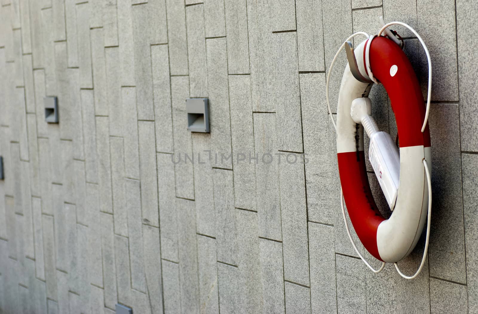 a red and white lifebuoy hanging on a stone wall