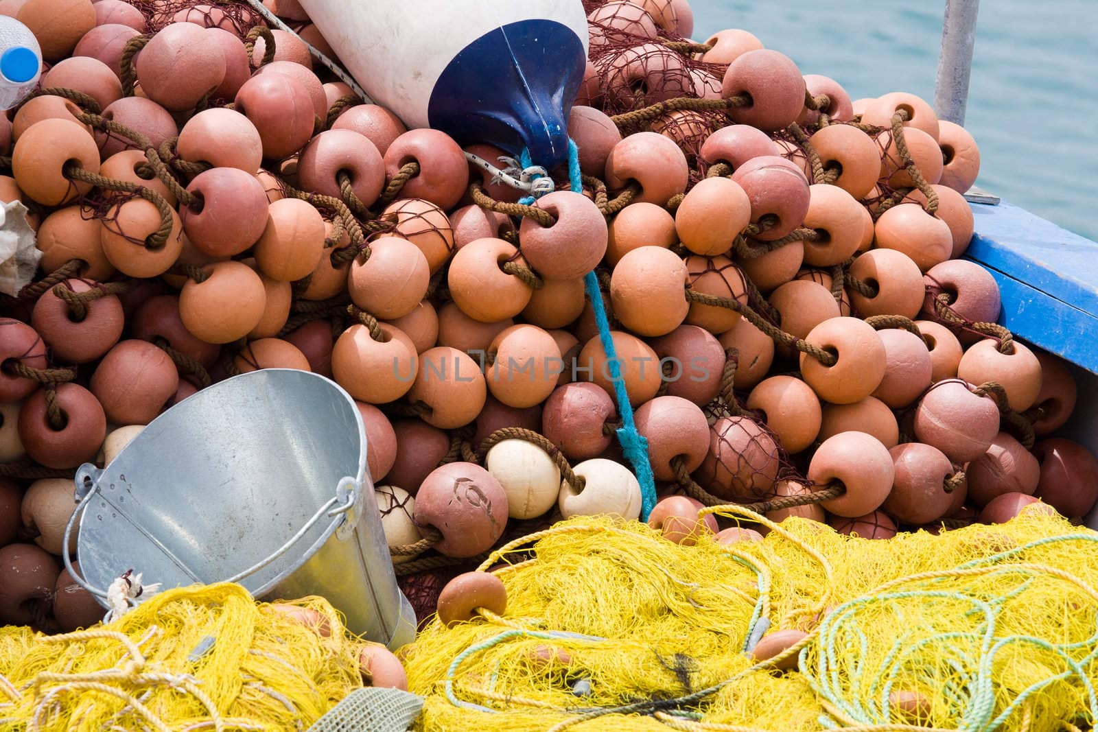 Nylon yellow  fishing net, metal bucket, buoy close-up on the boat desk