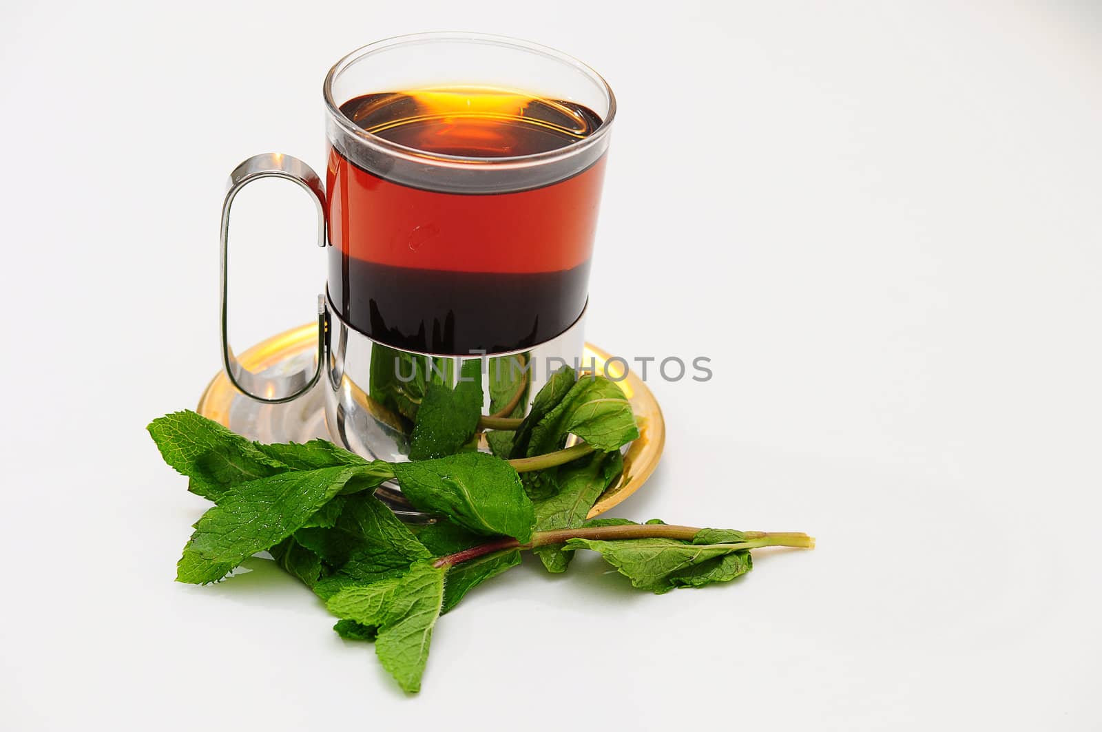 A glass of hot tea on a saucer.