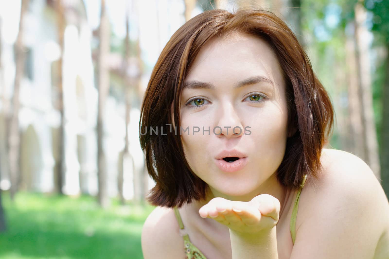 Close-up portrait of a young girl giving a kiss outdoors