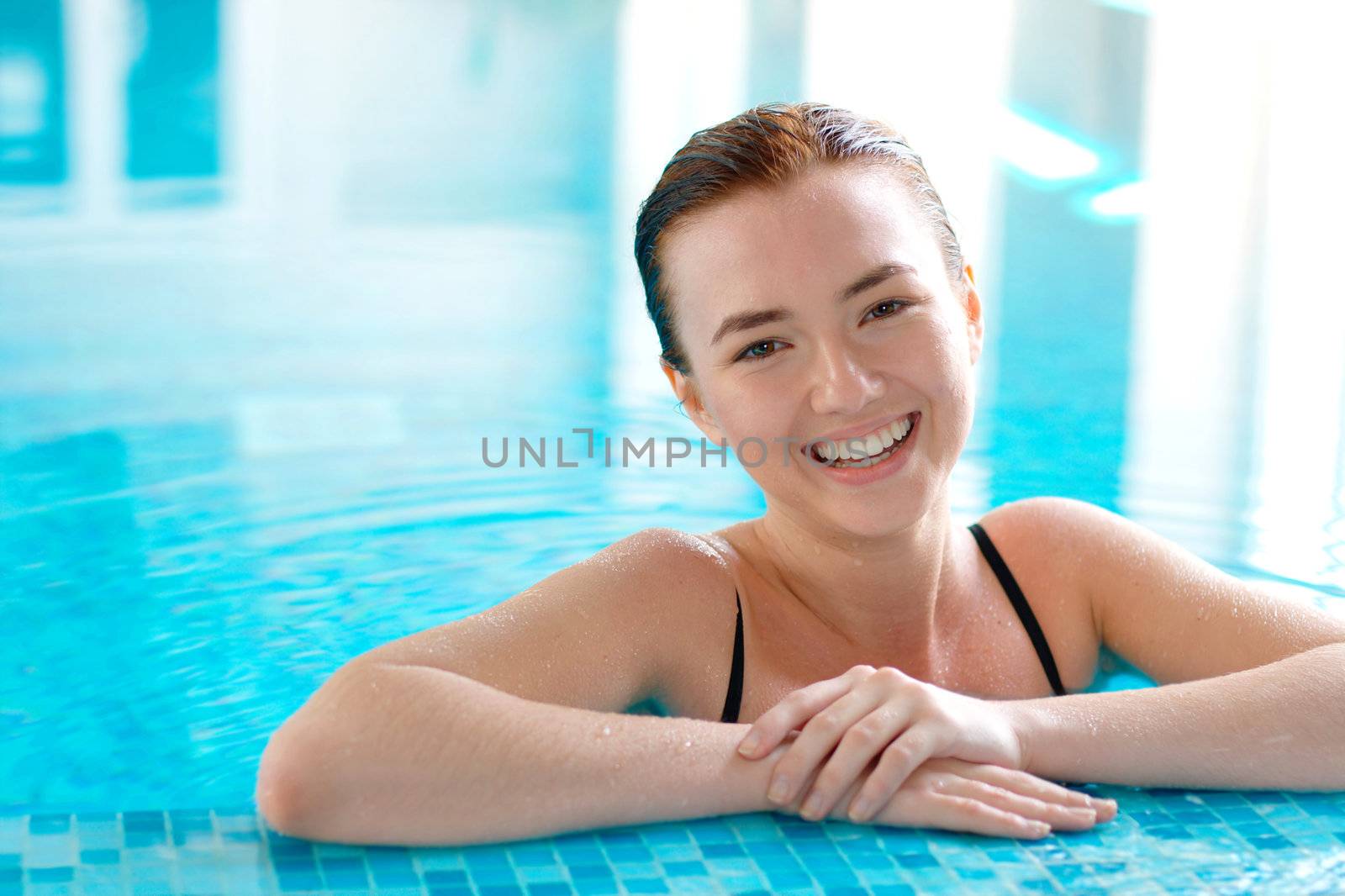 Close-up portrait of a smiling young beautiful girl at the swimming pool