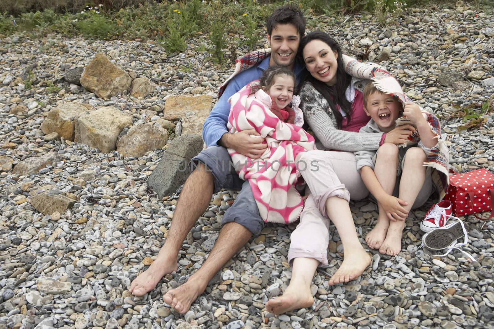 Family on beach with blankets by omg_images