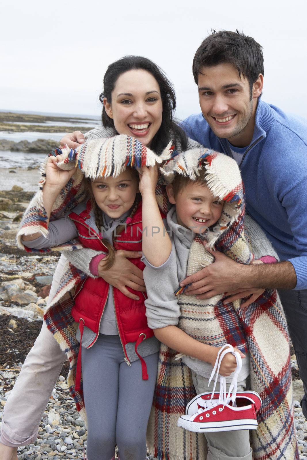 Family on beach with blankets by omg_images