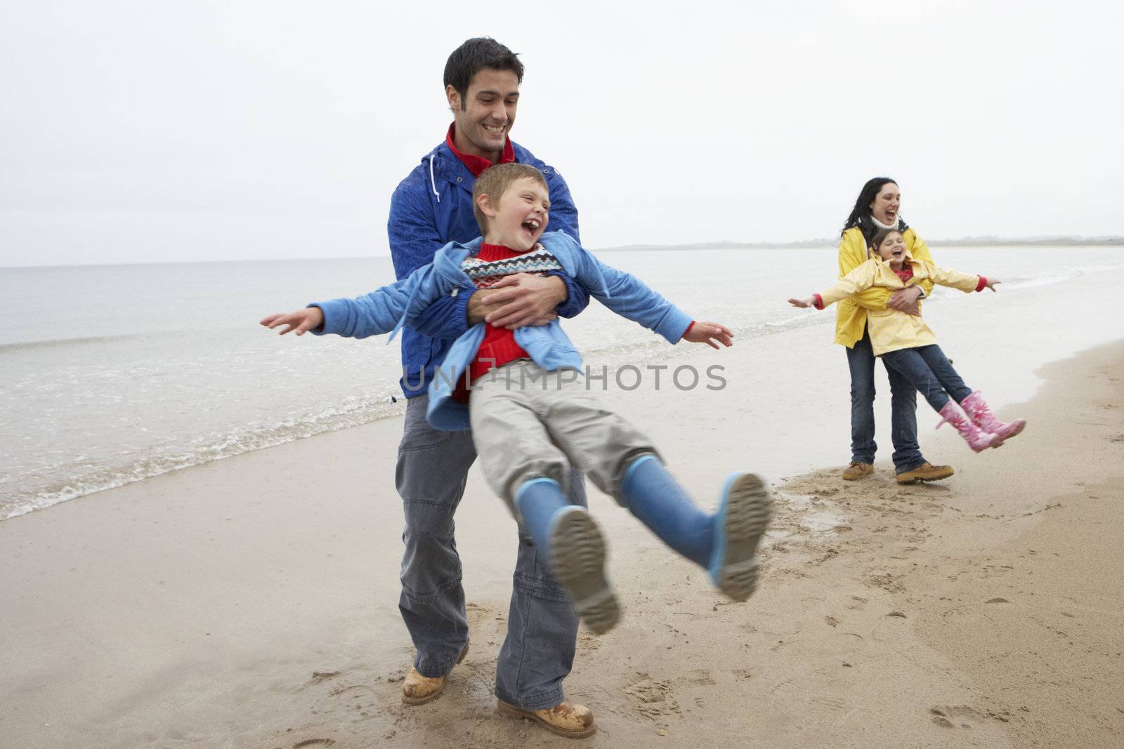 Family playing on beach by omg_images