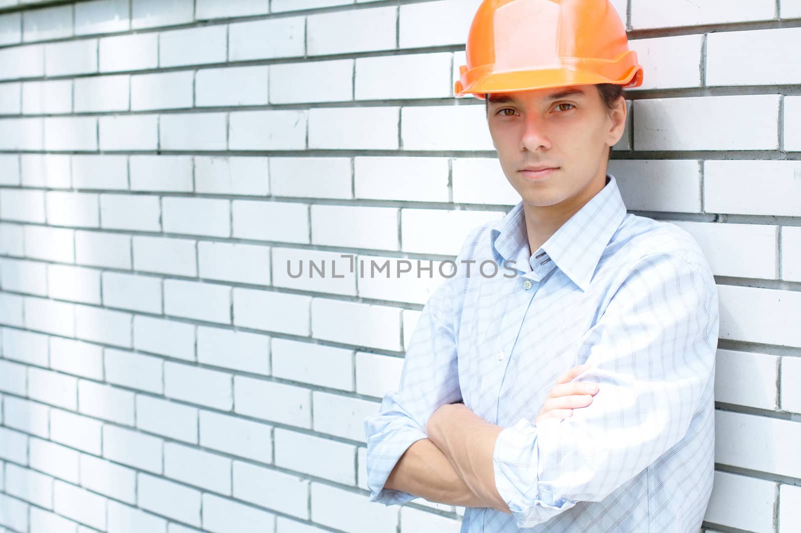 Close-up portrait of a young worker standing near a white wall with copy space