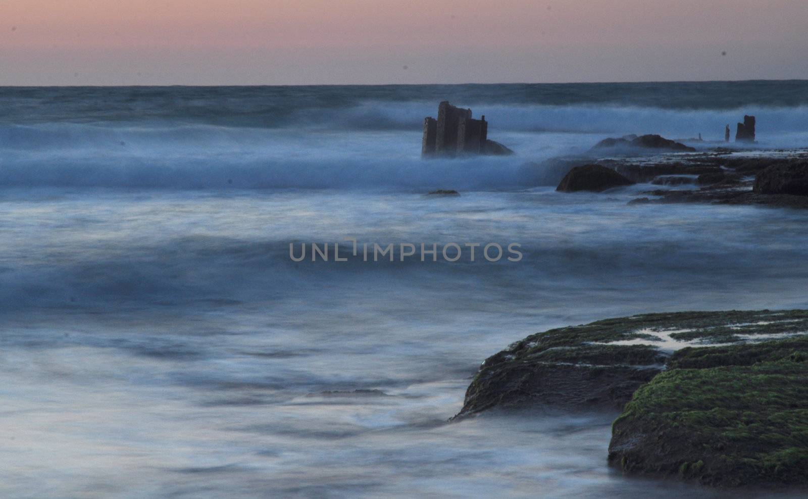 Sunset at Sea. Small waves. Stones overgrown with moss.