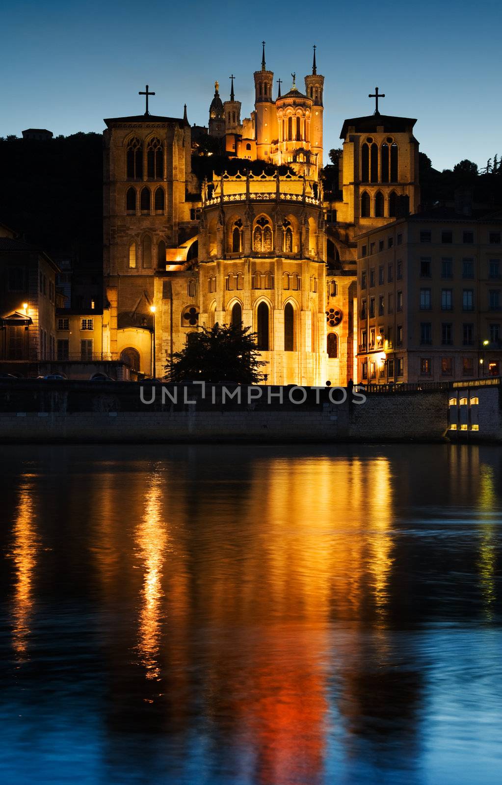 Early evening picture of the Notre Dame de Fourviere basilica and the St. Jean cathedral both illuminated and reflected on the waters of the river Saone, in Lyon, France