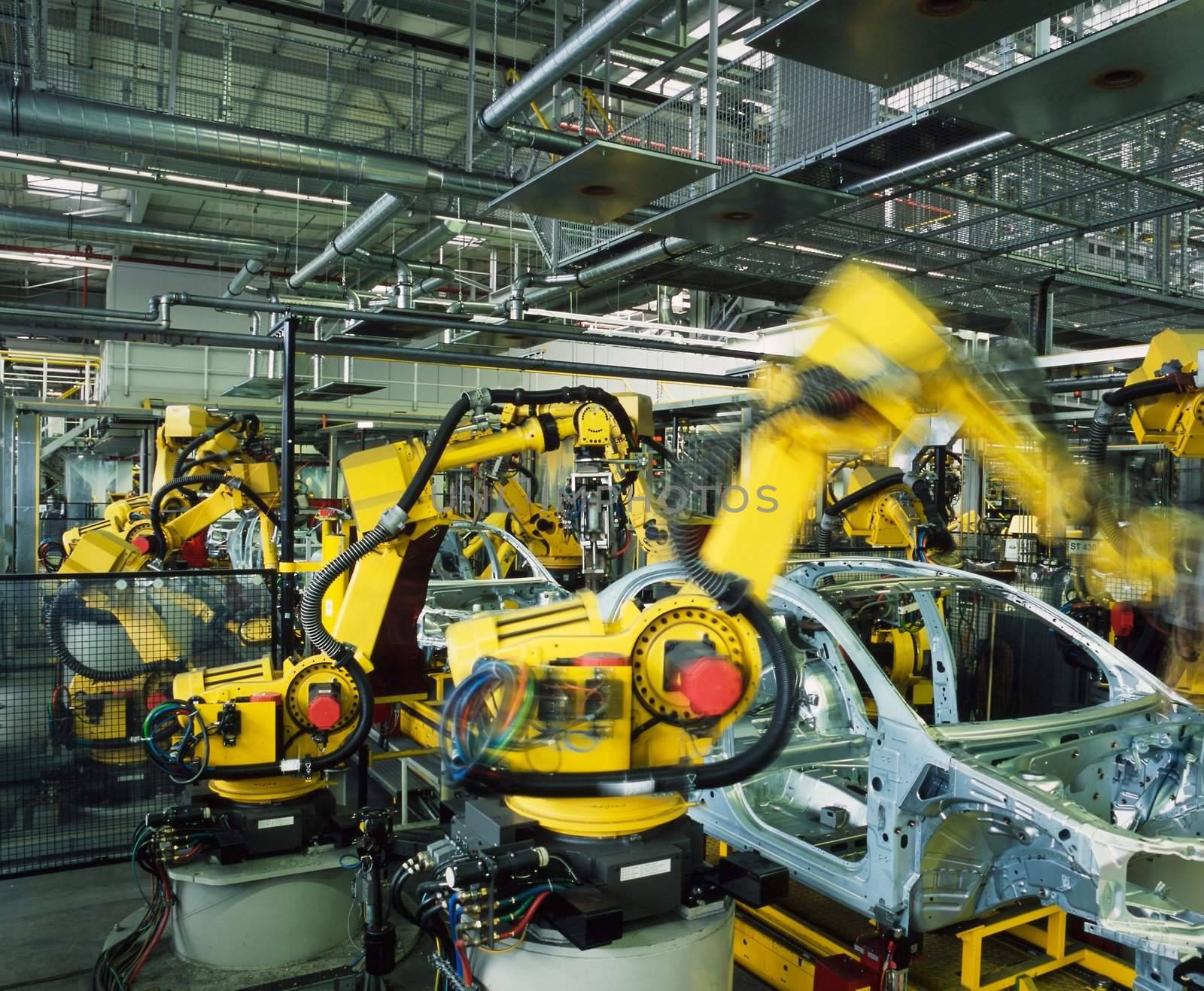 yellow robots welding cars in a production line