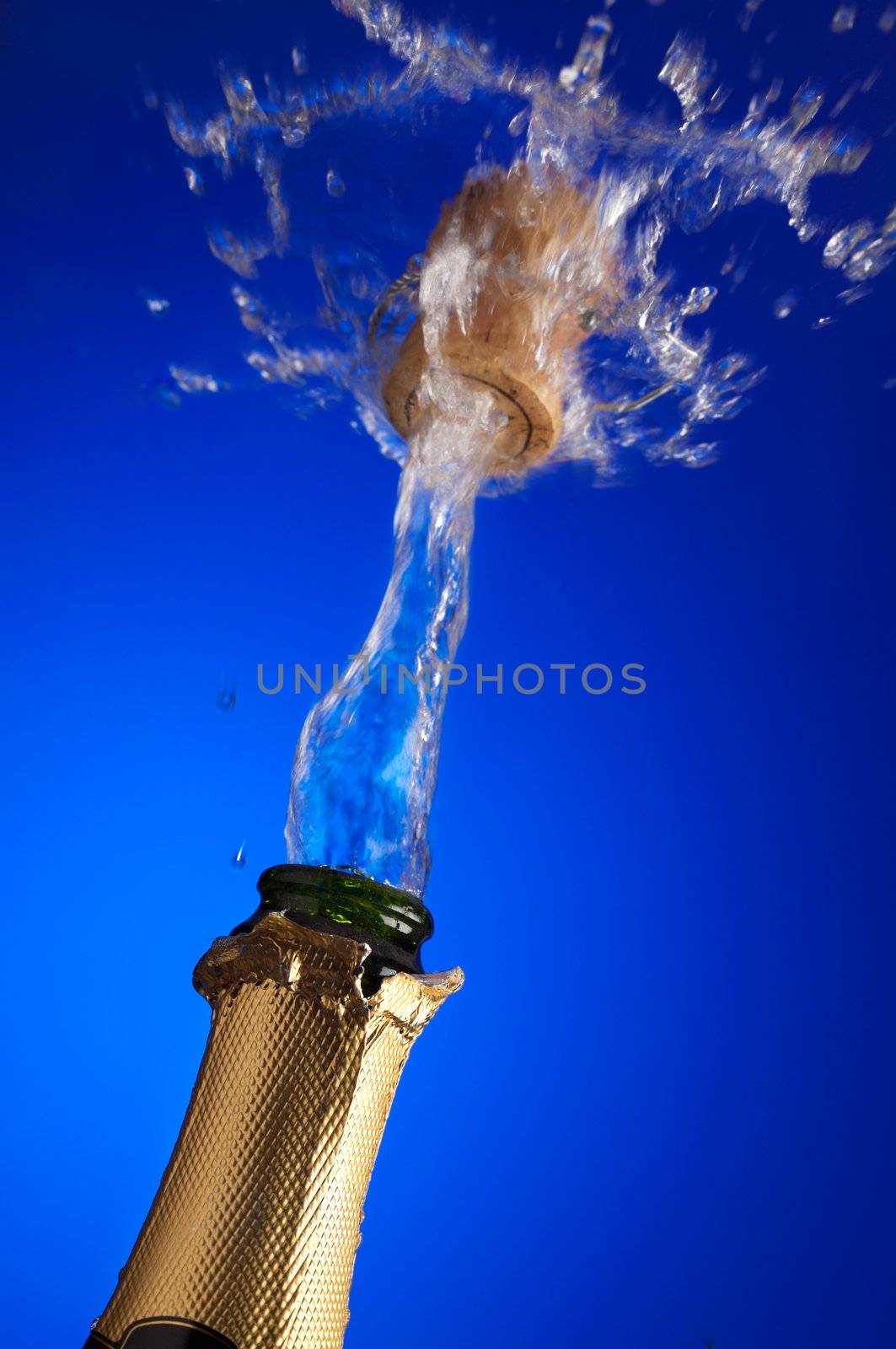 clos-up of an uncorked champagne bottle with cork flying away on the liquid