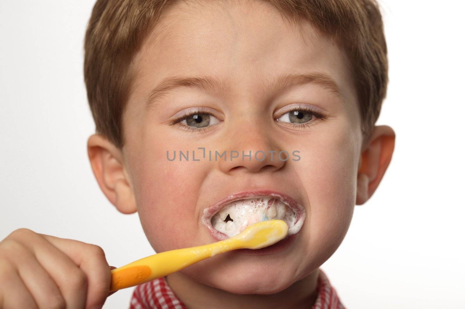 young boy brushing teeth by RainerPlendl